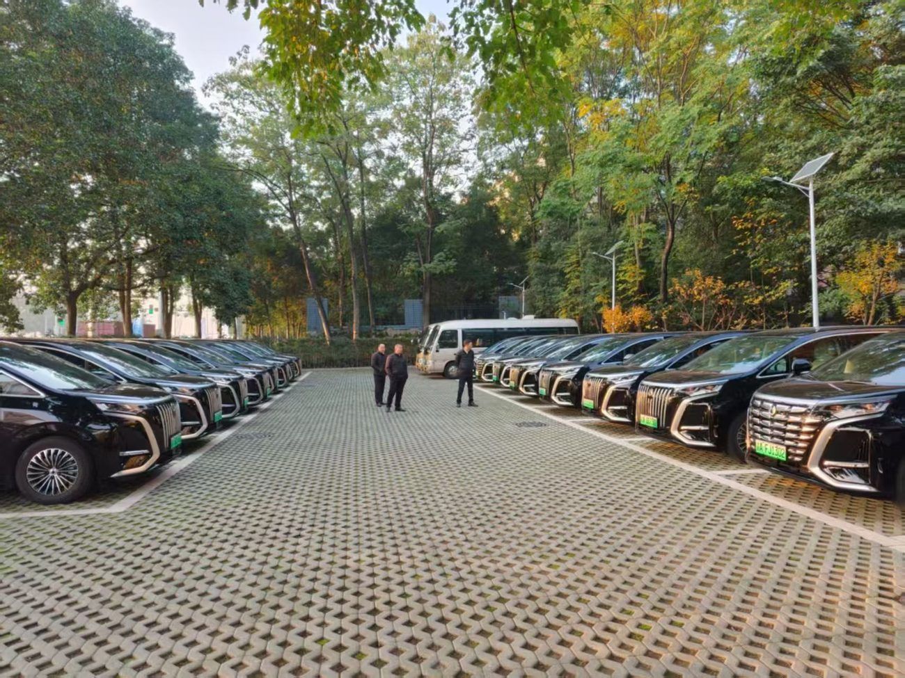 Our black MPVs and a white minibus, with three of our drivers